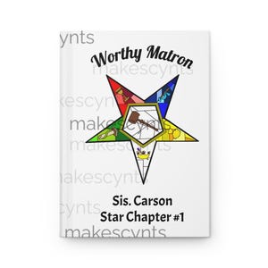 May include: A white journal with the words "Worthy Matron" and "Sis. Carson Star Chapter #1" printed on the cover. The journal features a colorful star design with various symbols and a gavel in the center.