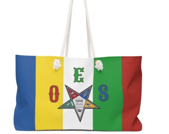 May include: Large tote bag with white rope handles. The bag features a colorful design with blue, yellow, green, and red vertical stripes. The center panel displays a star emblem and the letters OES.
