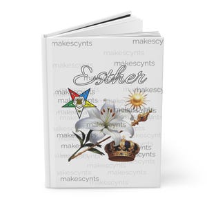 May include: White book with the name "Esther" written in cursive on the front cover. The book has a white background with a repeating pattern of the word "makescynts". The book also features a white lily, a gold crown, a yellow sun, and a five-pointed star with a red, white, and blue design.