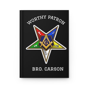 May include: Black journal with the words "WORTHY PATRON" and "BRO. CARSON" in white. The cover features a colorful star emblem with a central design including a compass, square, and the letter "G".