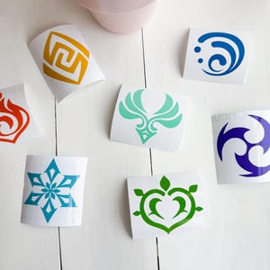 May include: Seven different vinyl stickers with various designs. The stickers are on white paper and feature a variety of colors, including blue, green, orange, purple, and yellow. The designs include a snowflake, a heart, a flame, a swirl, a bird, a spiral, and a three-pointed star.