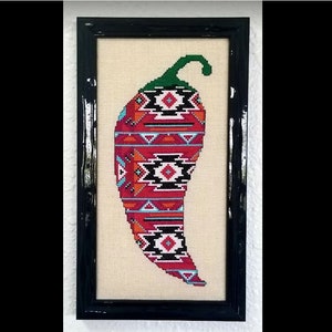 Könnte beinhalten: Ein gerahmtes Kreuzstichbild eines roten Chilischoten mit geometrischem Muster. Der Chilischote ist oben grün und hat einen schwarzen Rahmen.