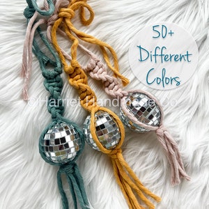 May include: Three handmade macrame keychains with silver disco ball charms. The keychains are made with green, yellow, and pink cotton cord. The text "50+ Different Colours" is visible in the image.