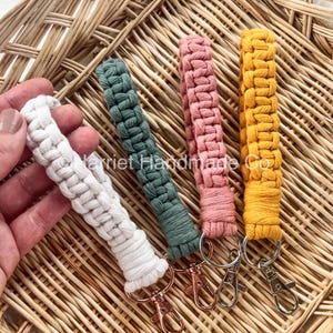May include: Four keychains with different colored braided cords and silver key rings. The cords are white, green, pink, and yellow.