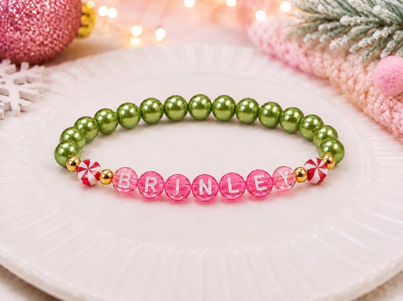 Puede incluir: Una pulsera de cuentas con una hilera de cuentas redondas de color verde oliva met&aacute;lico, seguida de una secci&oacute;n de cuentas de color rosa intenso transl&uacute;cido con el nombre BRINLEY en letras blancas, con espaciadores dorados y cuentas de menta.