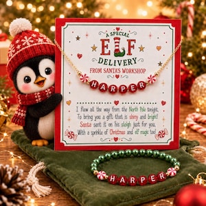 May include: A gold-tone necklace and a green and red beaded bracelet with the name HARPER, displayed on a card that reads A SPECIAL ELF DELIVERY FROM SANTA'S WORKSHOP, next to a plush penguin wearing a red and white knit hat and scarf.