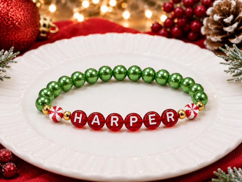 Puede incluir: Una pulsera de cuentas con una hilera de cuentas redondas de color verde met&aacute;lico, seguidas de cuentas rojas que deletrean el nombre HARPER en letras blancas, acentuadas con peque&ntilde;as cuentas espaciadoras doradas y dos cuentas blancas con rayas rojas.