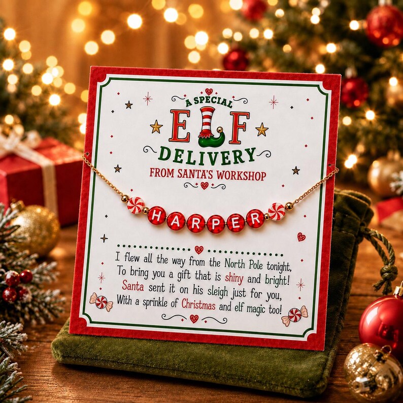 Puede incluir: Un collar de cuentas dorado con cuentas de letras rojas que deletrean HARPER y cuentas de caramelo de menta, presentado en una tarjeta blanca con bordes verdes y rojos. El texto dice A SPECIAL ELF DELIVERY FROM SANTA'S WORKSHOP.