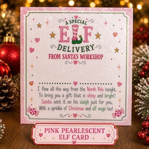 Puede incluir: Una tarjeta cuadrada de color rosa nacarado con el texto A SPECIAL ELF DELIVERY FROM SANTA'S WORKSHOP y un poema sobre el Polo Norte. Debajo, una etiqueta rectangular dice PINK PEARLESCENT ELF CARD. El dise&ntilde;o incluye corazones, estrellas y caramelos.