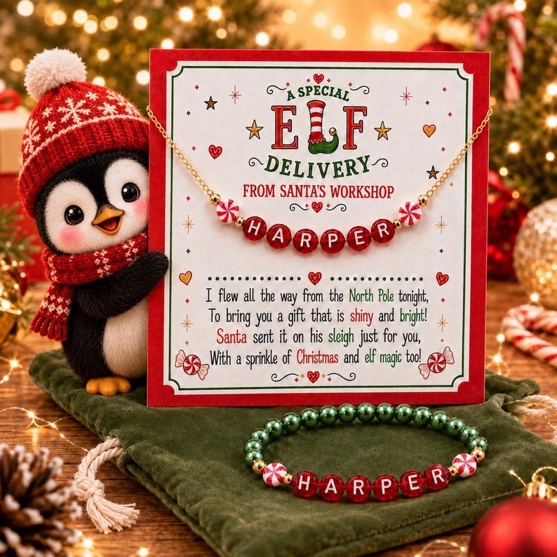 Puede incluir: Un collar dorado y una pulsera de cuentas verdes y rojas con el nombre HARPER, presentados en una tarjeta que dice A SPECIAL ELF DELIVERY FROM SANTA'S WORKSHOP, junto a un ping&uuml;ino de peluche con gorro y bufanda de punto rojo y blanco.