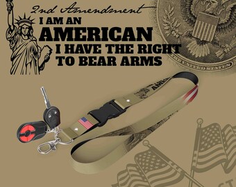 May include: A tan lanyard with a black buckle and a small American flag. The lanyard has a print of the Statue of Liberty and the text "2nd Amendment I AM AN AMERICAN I HAVE THE RIGHT TO BEAR ARMS".