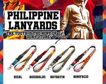 May include: Four lanyards featuring Philippine-themed designs labeled Rizal, Aguinaldo, Baybayin, and Bonifacio. Each lanyard includes a black plastic buckle and a silver metal lobster clasp. The background displays historical imagery and text.