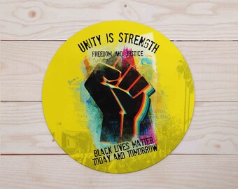 May include: A yellow circle with the text "Unity is Strength", "Freedom and Justice", "Black Lives Matter", and "Today and Tomorrow". A black fist with rainbow colored accents is in the center of the circle.