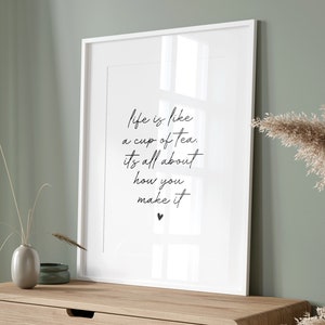 Puede incluir: Una impresi&oacute;n enmarcada con la cita "La vida es como una taza de t&eacute;, se trata de c&oacute;mo la preparas" en escritura negra sobre fondo blanco. La impresi&oacute;n est&aacute; colgada en una pared verde claro sobre una c&oacute;moda de madera con tres cajones.