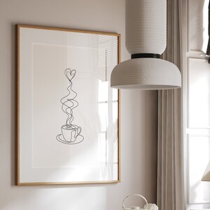 May include: A white ceramic pendant light hangs over a dining table with a white marble top and gold accents. Two wicker chairs are placed on either side of the table. A framed print with a line drawing of a coffee cup with hearts for steam hangs on the wall behind the table.