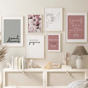 May include: A set of six framed prints with various designs and text. The prints are hung on a white wall above a white dresser with a white wicker basket and a white lamp. The prints feature a floral design, a line drawing of two faces, a gray background with the text "sweet dreams", a pink background with the text "if you really love me you'll let me sleep", a pink background with the text "this is our happy place", and a white background with the text "morning gorgeous".
