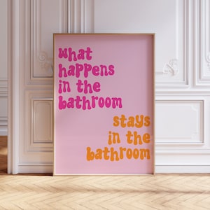 May include: A pink and orange framed print with the text "what happens in the bathroom stays in the bathroom".
