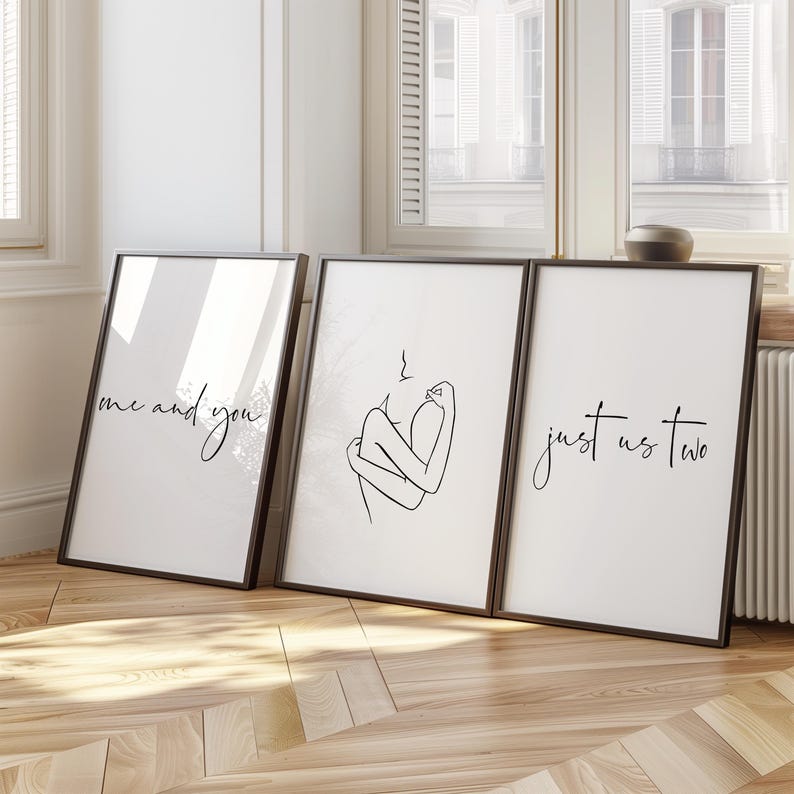 May include: Three black framed prints with white backgrounds. The left print has the text "me and you" in black cursive. The middle print has a line drawing of two people embracing. The right print has the text "just us two" in black cursive.