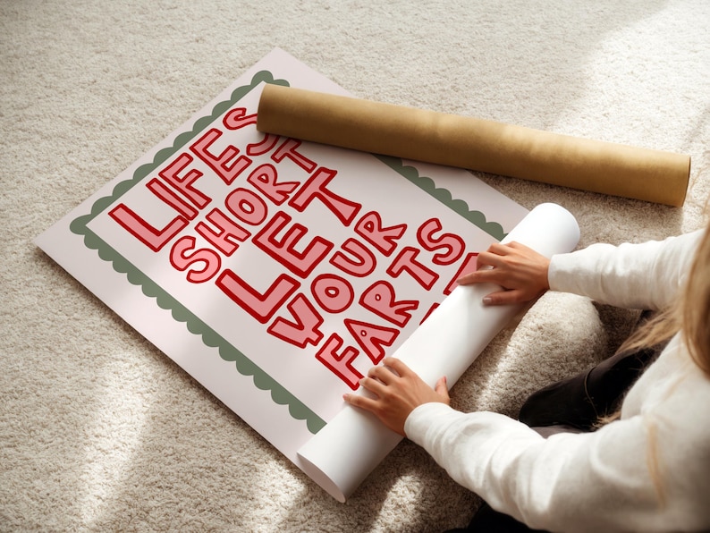 May include: A poster with the text "LIFE'S SHORT LET YOUR FARTS" in red letters. The poster is being unrolled, revealing the message. A rolled-up poster is also visible. The poster has a scalloped green border.