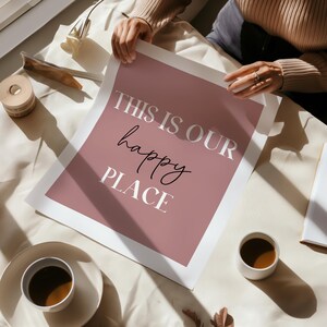 May include: A pink and white printable wall art print with the text "This is our happy place".
