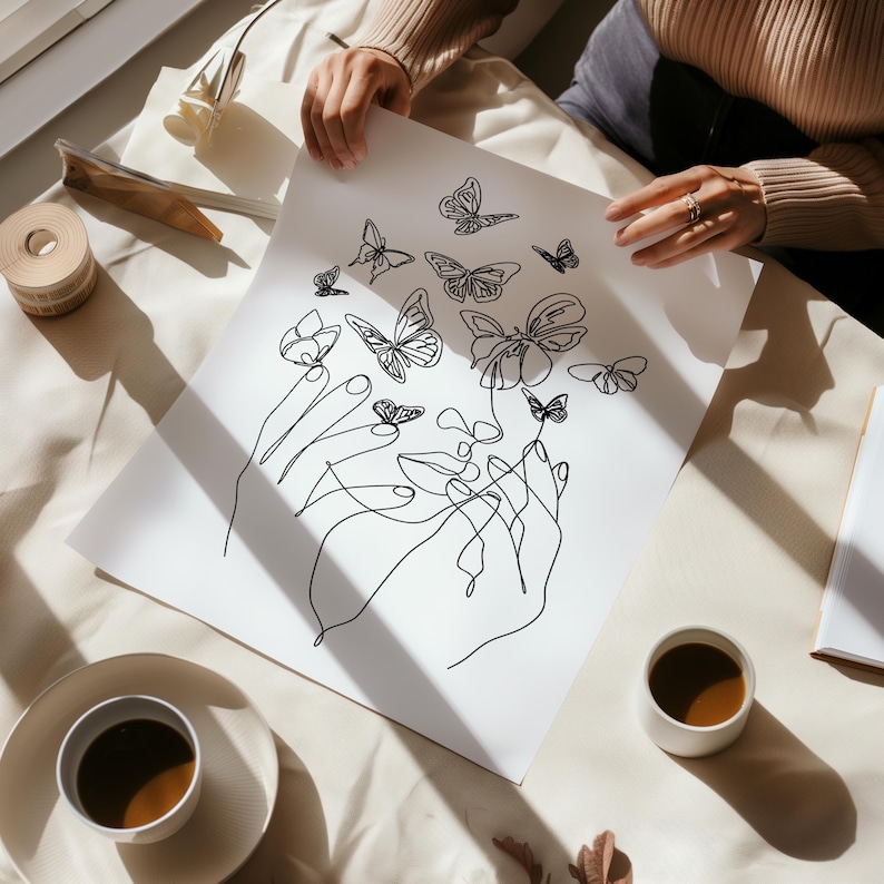 May include: A white sheet of paper with a black line drawing of two hands holding a bouquet of butterflies. The butterflies are drawn in a simple, elegant style.