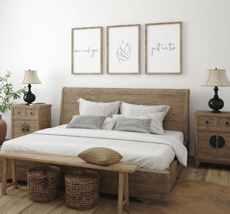 May include: Three framed prints with minimalist line art and text. The prints are hung on a white wall above a wooden bed frame with a white duvet and pillows. The text on the prints reads "me and you", "just us two", and a line drawing of two figures embracing.