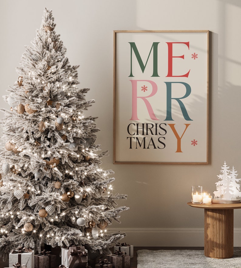 May include: A snowy Christmas tree with gold and white ornaments, a framed print with the text "Merry Christmas" in colorful letters, and a small wooden table with candles and a white paper Christmas tree decoration.