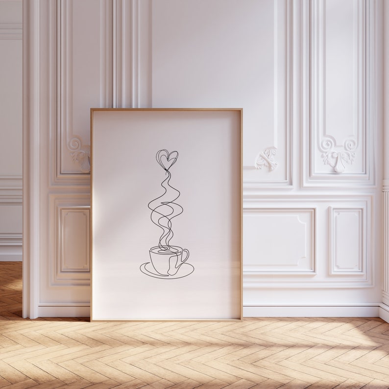 May include: A black and white line drawing of a coffee cup with steam rising in the shape of a heart. The drawing is framed in a gold frame and is hanging on a white wall.