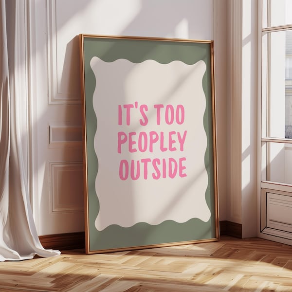 以下が含まれることがあります： ピンク色の文字で「IT'S TOO PEOPLEY OUTSIDE」と書かれた額入りのアートプリント。テキストは、波状の緑色のボーダーが付いたクリーム色の背景にあり、金色のフレームに収められています。アートワークは、窓と白いカーテンのある壁に立てかけられています。