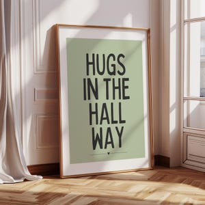 May include: A sage green poster with black text that reads "HUGS IN THE HALL WAY" with a small heart symbol at the bottom.