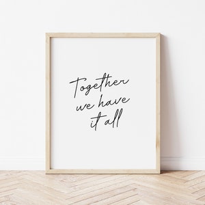 May include: A framed print with the words "Together we have it all" in black script on a white background. The frame is a light wood color, and the print is displayed against a white wall and a wooden floor.