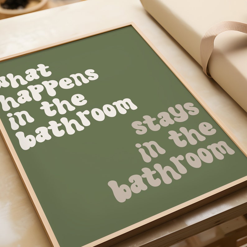 May include: A framed print with a green background and white text that reads "What happens in the bathroom stays in the bathroom".