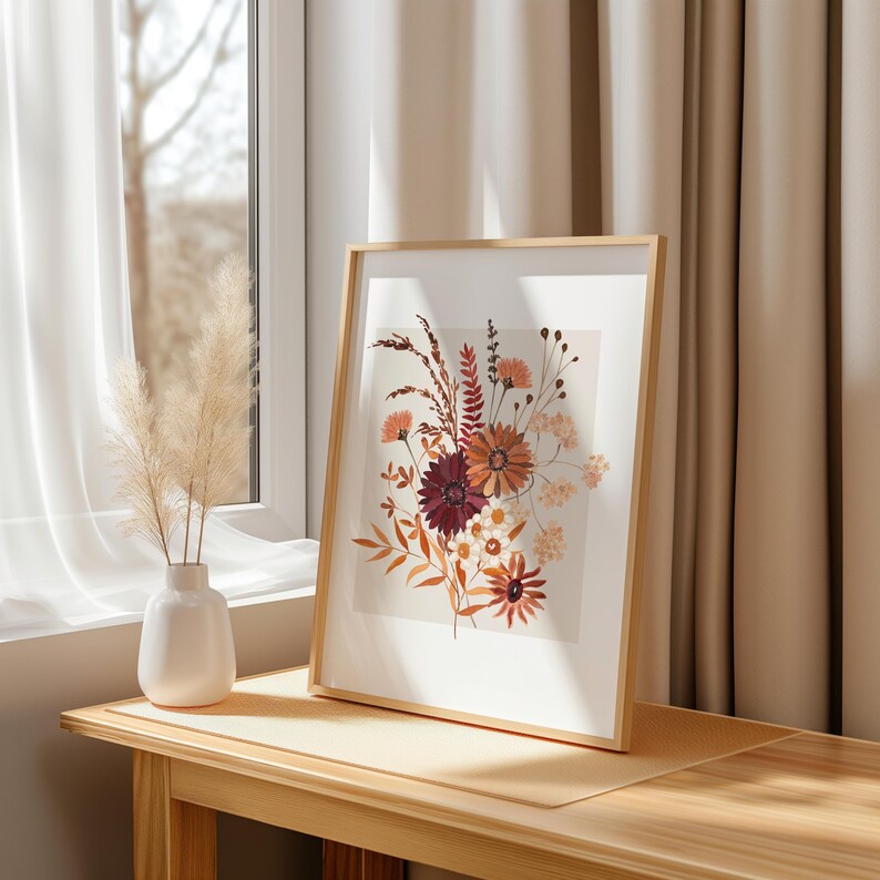 May include: A framed print of a floral arrangement with dried flowers in shades of red, orange, and brown. The flowers are arranged in a vase and are set against a white background.