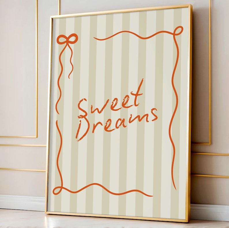 May include: A framed print with a beige and white striped background. The print features an orange ribbon border with the words "Sweet Dreams" written in orange cursive.