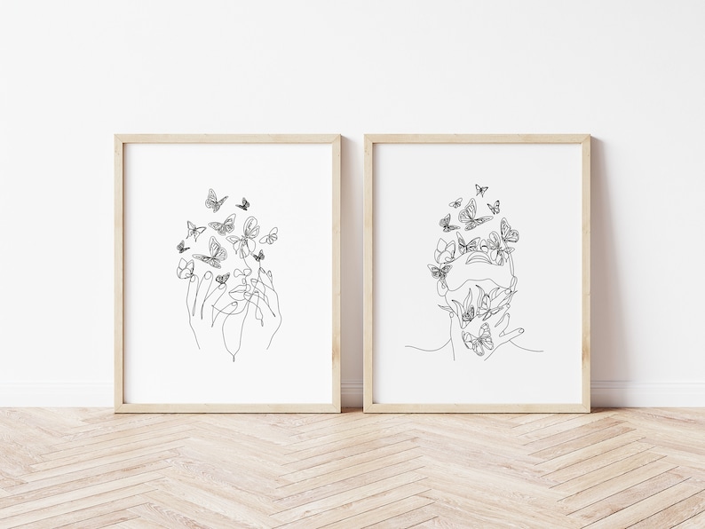 May include: Two black and white line art prints of a face with butterflies surrounding it. One print shows a face with hands covering the eyes, the other shows a face with hands covering the mouth.