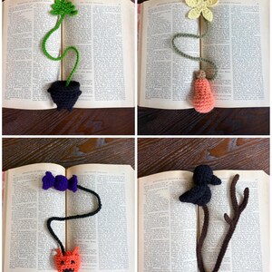 May include: Four handmade crochet bookmarks displayed in an open book. The bookmarks feature various designs: a green plant in a black pot, a yellow flower with a peach-colored object, a purple bow with an orange devil, and a black bird on a brown branch.