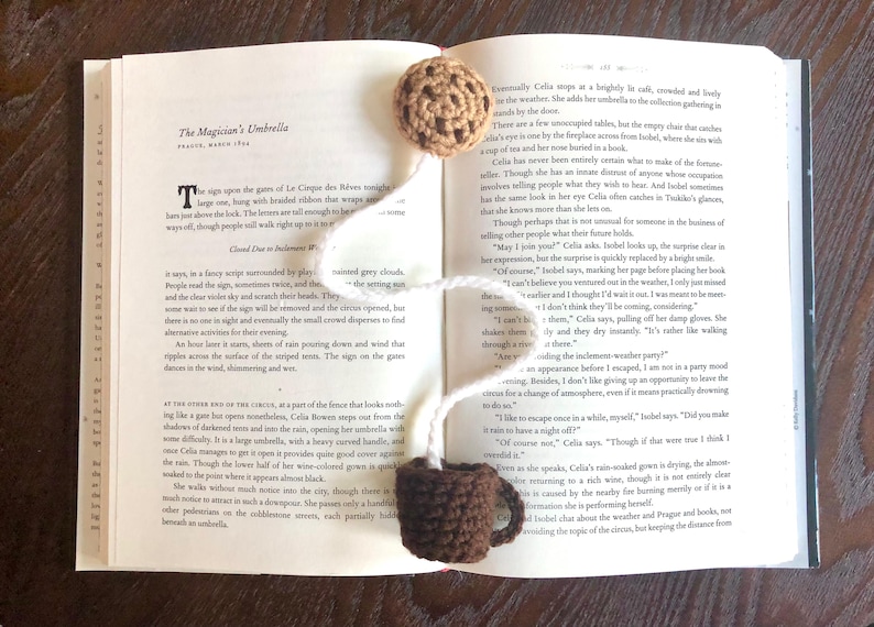 A chocolate chip cookie and mug crochet bookmark. Bookmark is sitting across a book and the bookmark string is white like milk.