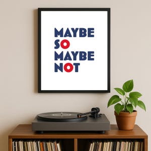 Può includere: Una stampa incorniciata con le parole "MAYBE SO MAYBE NOT" in blu e rosso. La stampa è esposta sopra un giradischi su un mobile di legno. Una piccola pianta in vaso si trova a destra del giradischi.