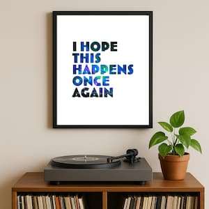 Puede incluir: Una impresión enmarcada con el texto "I HOPE THIS HAPPENS ONCE AGAIN" en azul y verde. La impresión está encima de un tocadiscos en un mueble de madera con una planta en maceta.