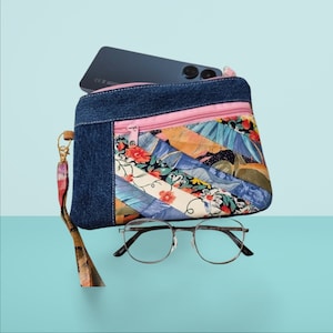 Peut inclure: Une pochette en tissu denim et floral avec une fermeture éclair rose. La pochette a une sangle et est conçue pour contenir un téléphone.