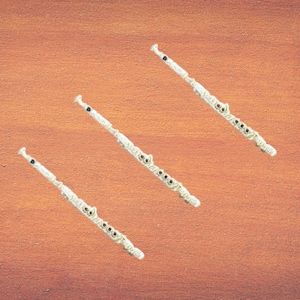 May include: Three silver flutes arranged in a diagonal line on a brown wooden surface.