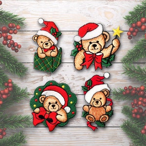 May include: Four embroidered Christmas ornaments featuring brown teddy bears wearing red Santa hats and holding red bows. The ornaments are surrounded by green holly leaves and red berries.