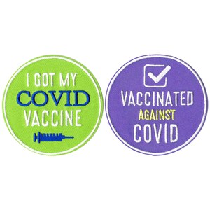 Op de afbeelding: Twee ronde geborduurde patches. De linker patch is limoengroen met een witte rand, voorzien van de tekst I GOT MY COVID VACCINE in blauw en wit, en een blauw spuitpictogram. De rechter patch is paars met een witte rand en een vinkje.