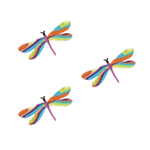 May include: Three embroidered dragonfly patches featuring vibrant, multi-colored wings with horizontal stripes in shades of orange, blue, green, and purple. Each dragonfly has a slender pink body and black antennae, rendered in a detailed stitch.