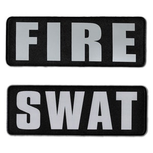 May include: Two rectangular patches with black fabric backgrounds and rounded corners. The top patch features the word FIRE in large, bold, light gray capital letters. The bottom patch features the word SWAT in large, bold, light gray capital letters.