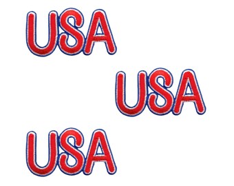以下が含まれることがあります： 太い赤色のフォントで「USA」の文字が刺繍されたワッペンが3つ。縁取りは厚い青色で、各ワッペンは同一のデザインです。丸みを帯びたサンセリフ体の書体で、ステッチによる質感のある仕上がりになっています。