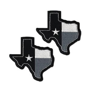 Puede incluir: Dos parches bordados con la forma del estado de Texas. Cada parche presenta un diseño en negro y gris con una estrella blanca en el centro. Los parches tienen un borde cosido blanco.