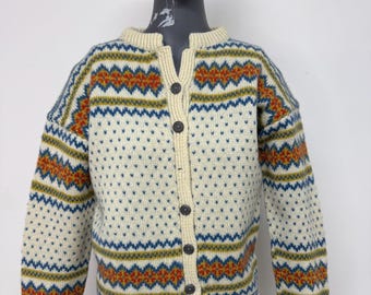 Könnte beinhalten: Cremefarbene Strickjacke mit Rundhalsausschnitt und Knopfleiste. Das Muster ist geometrisch in Orange, Blau und Grün gehalten. Der Pullover mit langen Ärmeln wird auf einer Schaufensterpuppe präsentiert. Maße in Zentimetern.