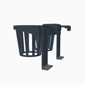 May include: A dark gray, dual cup holder designed for a vehicle. The cup holders are cylindrical with vertical slats. The base has two legs with a flat bottom and a hook on the side for securing the holder.