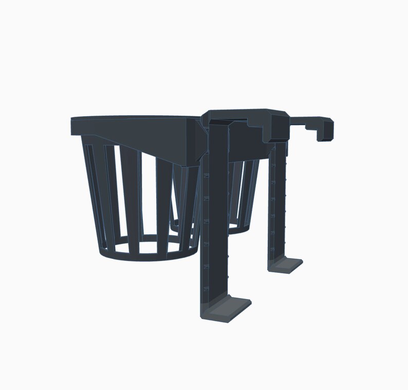 May include: A dark gray, dual cup holder designed for a vehicle. The cup holders are cylindrical with vertical slats. The base has two legs with a flat bottom and a hook on the side for securing the holder.